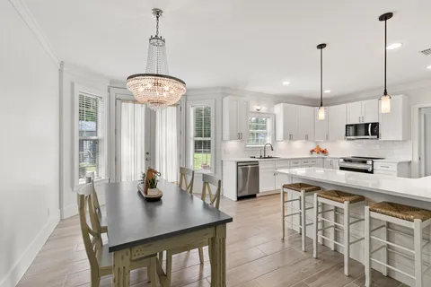 a kitchen with stainless steel appliances kitchen island granite countertop a table chairs and a refrigerator
