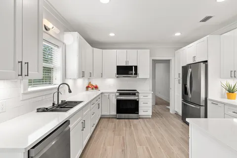 a kitchen with refrigerator a sink and wooden floor