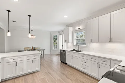 a kitchen with white cabinets and sink