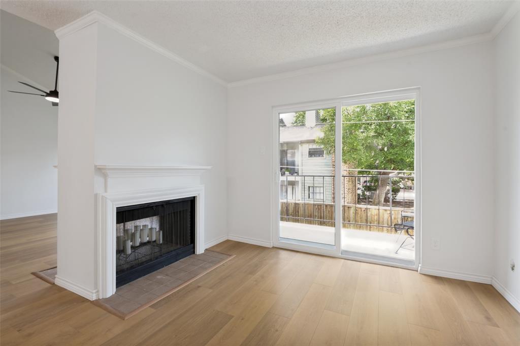 5300 Keller Springs Road, Unit 2042 Dallas, TX 75248 - Photo 10 of 28 Living area with light wood-finish flooring, white crown molding, and a fireplace featuring a white mantel and hearth