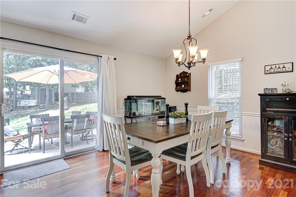 10715 Spruce Mountain Road Charlotte, NC 28214 - Photo 11 of 33 a dining room with wooden floor a chandelier a wooden table and chairs