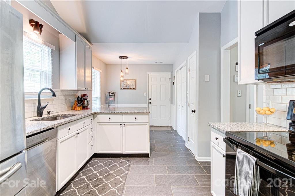 10715 Spruce Mountain Road Charlotte, NC 28214 - Photo 3 of 33 a large kitchen with a sink and dishwasher a stove top oven with wooden floor