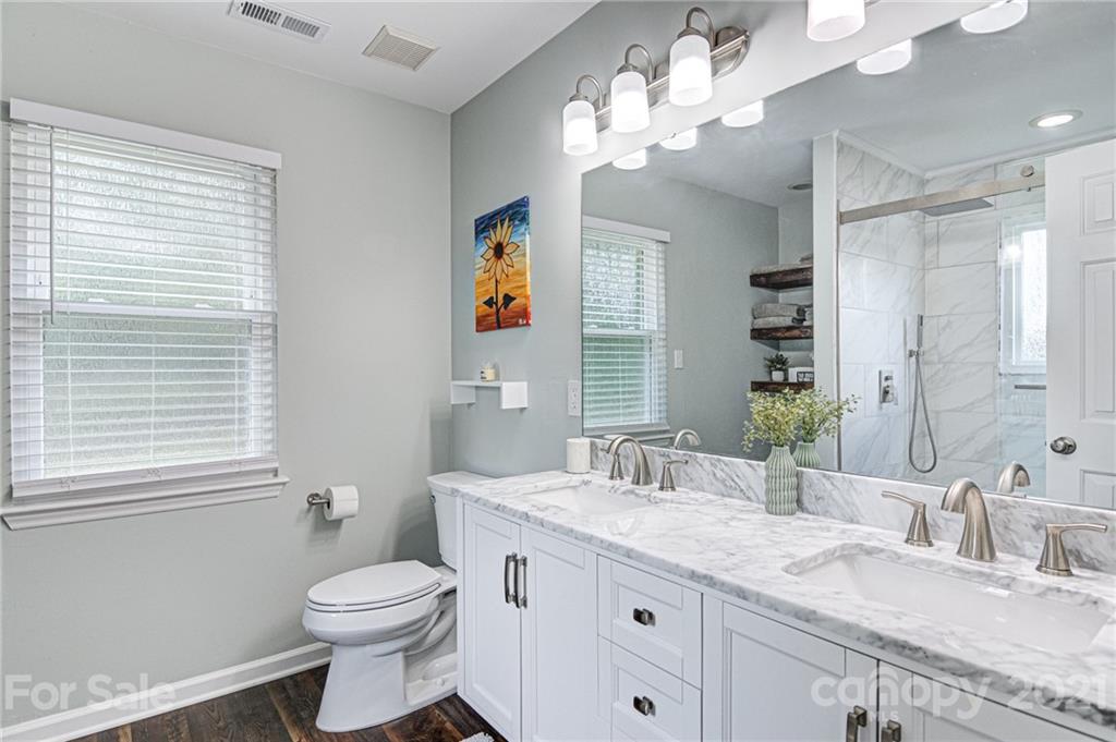 10715 Spruce Mountain Road Charlotte, NC 28214 - Photo 21 of 33 a bathroom with a granite countertop toilet a sink and a large mirror