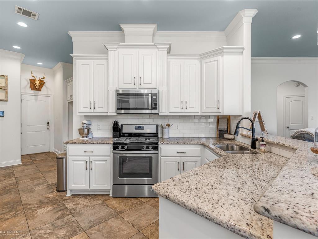 690 Lessie Drive Stonewall, LA 71078 - Photo 10 of 29 Kitchen featuring white cabinetry, stainless steel appliances, a subway tile backsplash, granite countertops, and tile flooring