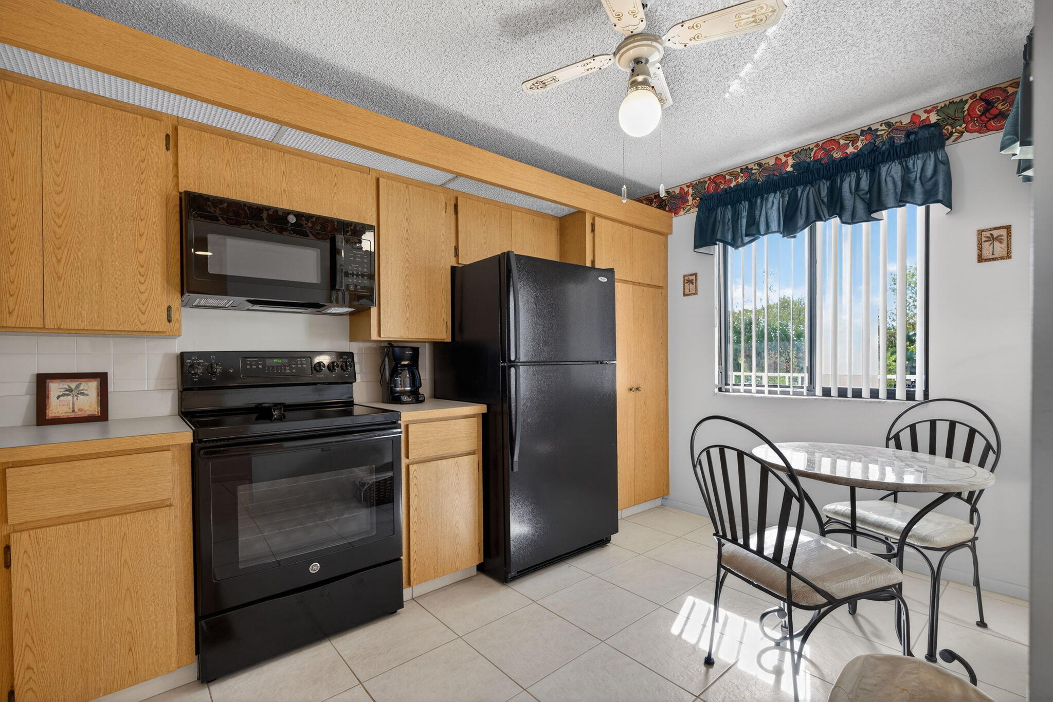 2601 Village Boulevard, Unit 303 West Palm Beach, FL 33409 - Photo 3 of 23 a kitchen with stainless steel appliances granite countertop a refrigerator a stove a microwave oven with a dining table and chairs