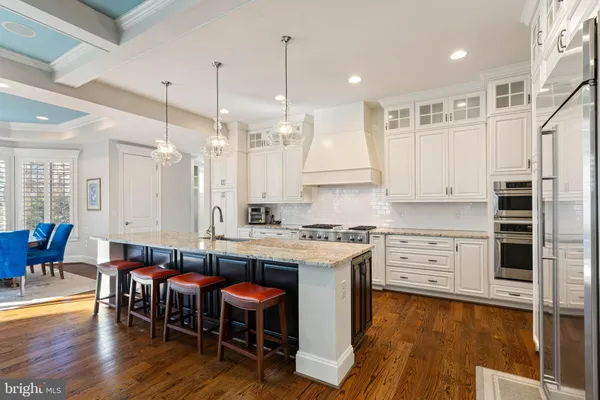 a kitchen with stainless steel appliances granite countertop a table chairs sink and cabinets