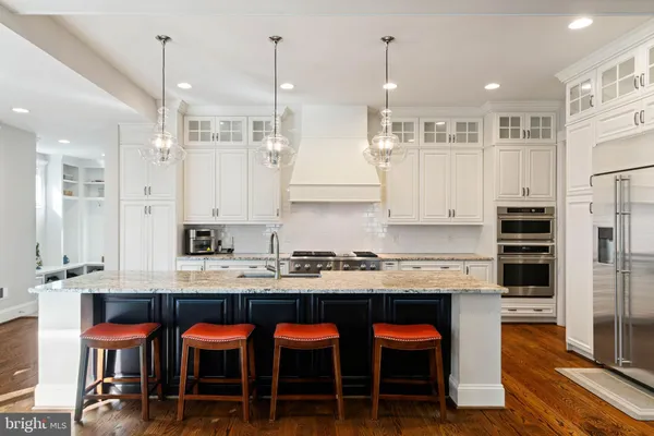 a large kitchen with stainless steel appliances granite countertop a stove a sink dishwasher and a dining table with the kitchen island