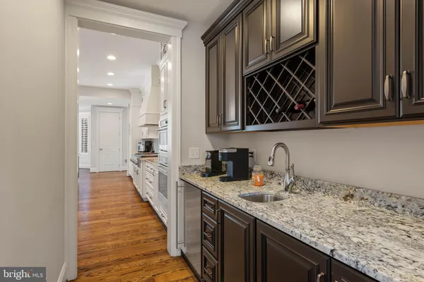 a large kitchen with granite countertop a stove a sink a center island and wooden floor
