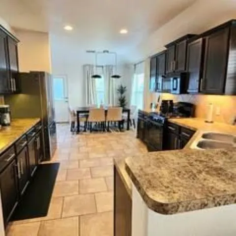 a kitchen with stainless steel appliances kitchen island granite countertop a table chairs sink and cabinets