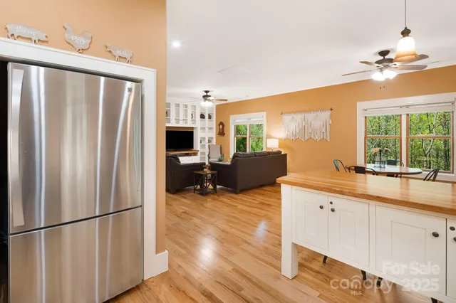 a kitchen with stainless steel appliances granite countertop a refrigerator a sink dishwasher a dining table and chairs with wooden floor