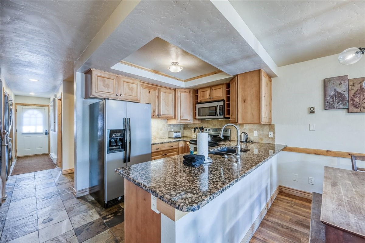 200 North Ridge Street, Unit R A Breckenridge, CO 80424 - Photo 7 of 38 a kitchen with stainless steel appliances granite countertop a refrigerator a stove and a sink with granite countertops
