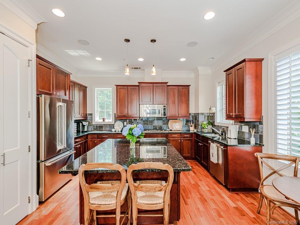 2223 Croydon Road, Unit 204 Charlotte, NC 28207 - Photo 12 of 27 a kitchen with a refrigerator a stove top oven and a dining table with wooden floor