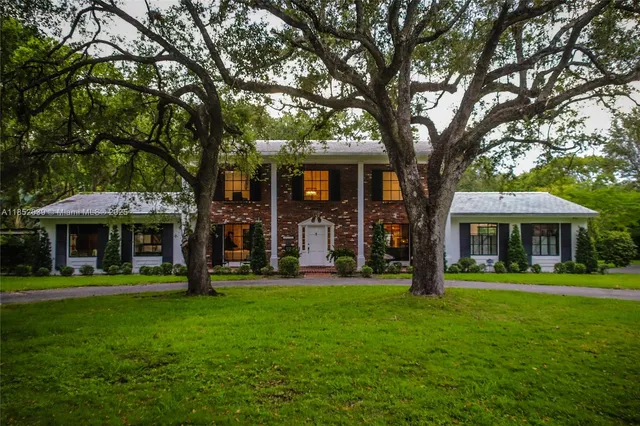a front view of a house with a garden and trees
