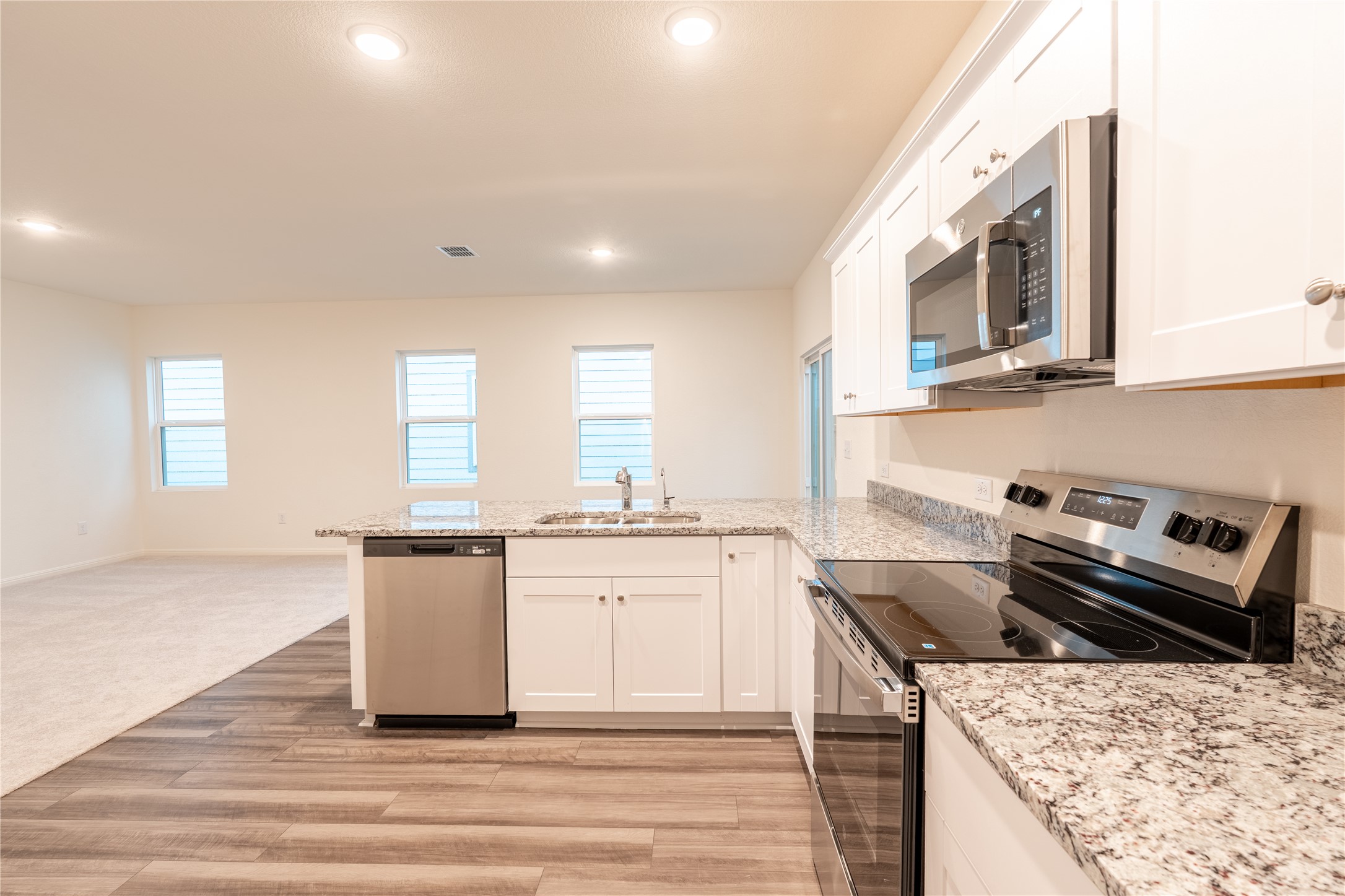 144 Mullen Way Taylor, TX 76574 - Photo 3 of 26 a kitchen with stainless steel appliances granite countertop a stove a sink and a microwave