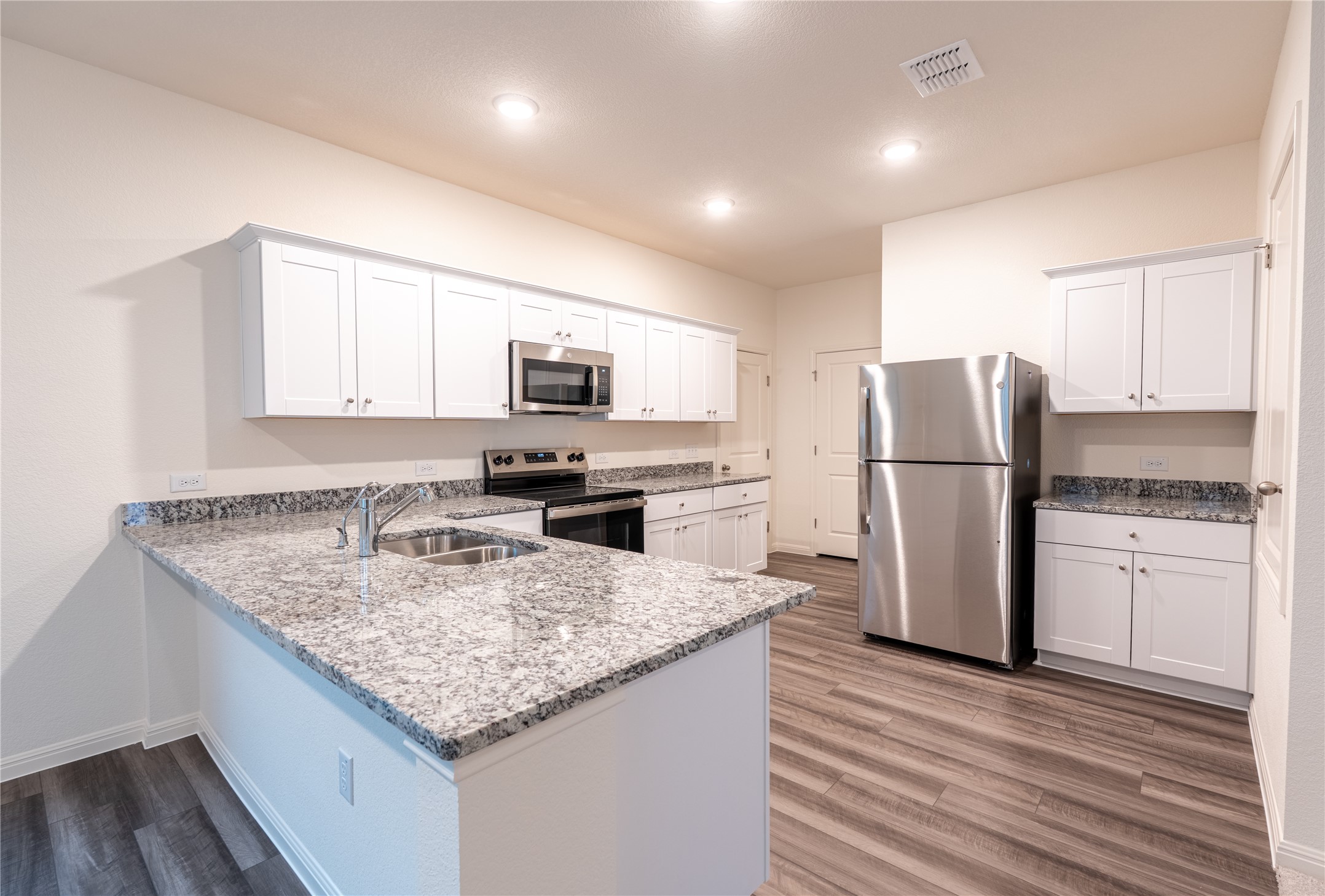 144 Mullen Way Taylor, TX 76574 - Photo 4 of 26 a kitchen with a refrigerator a stove top oven a sink and cabinets