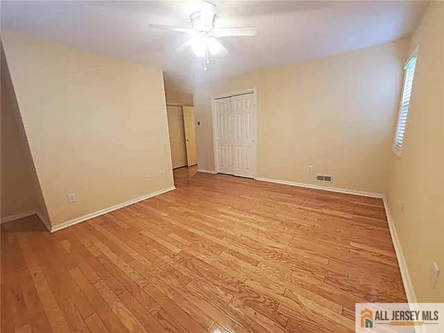 an empty room with wooden floor and fan