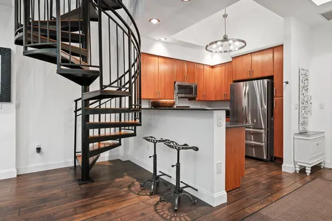 a view of kitchen with stainless steel appliances granite countertop cabinets and wooden floor