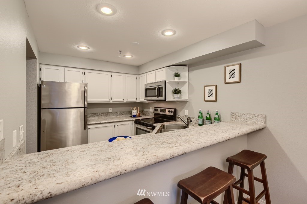19410 Bothell Way Northeast, Unit D202 Bothell, WA 98011 - Photo 6 of 26 a kitchen with granite countertop a refrigerator and a sink