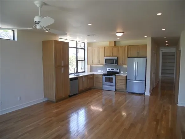 a kitchen with stainless steel appliances granite countertop a refrigerator a sink a stove a microwave and island with wooden floor