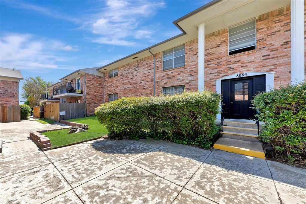 a view of a brick house with a yard and plants