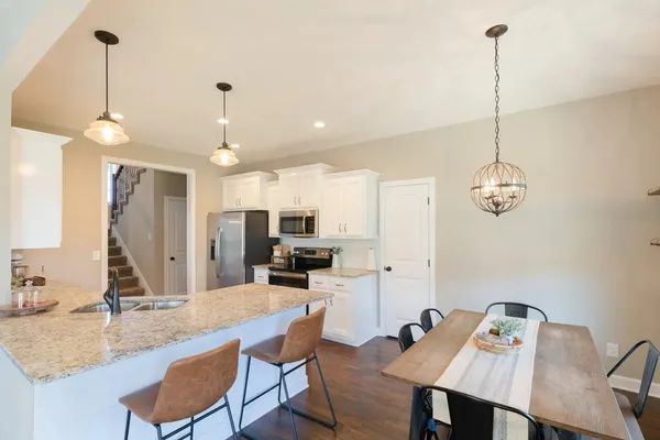 a kitchen with kitchen island a dining table chairs a sink and a chandelier