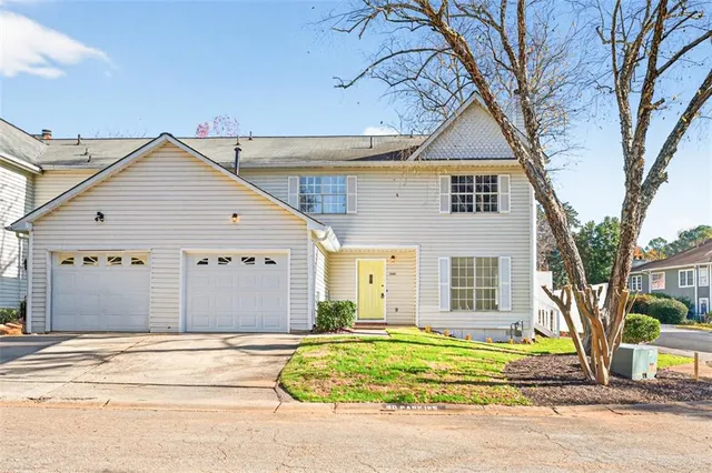 a view of a white house with a large tree and wooden fence