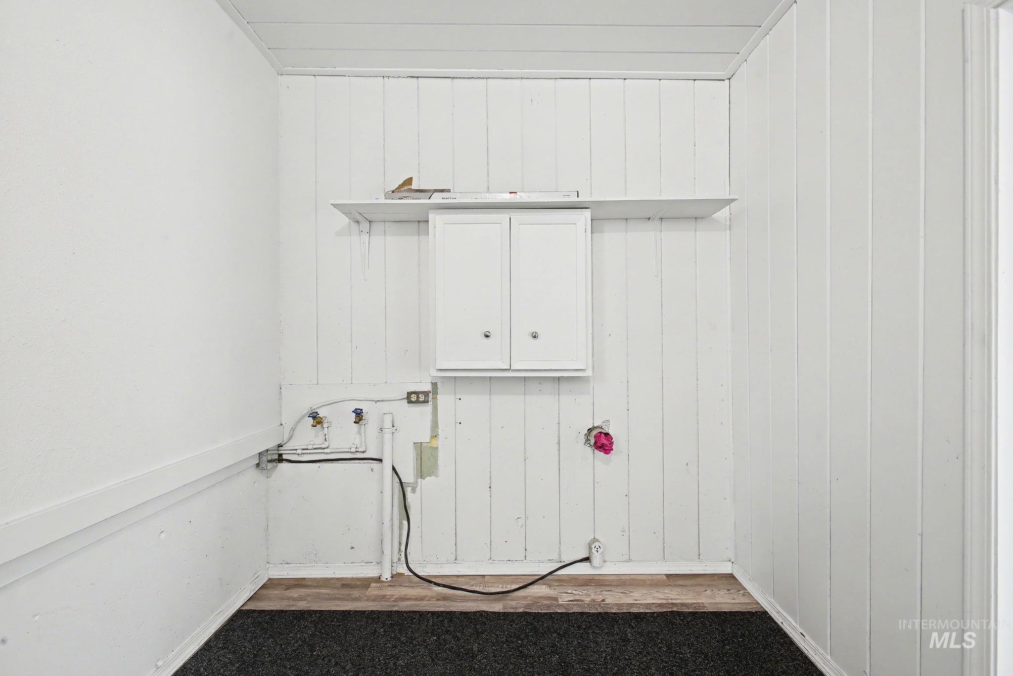 150 Elm Street Orofino, ID 83544 - Photo 19 of 36 Laundry area with wood walls, cabinet space, washer hookup, and dark wood-type flooring