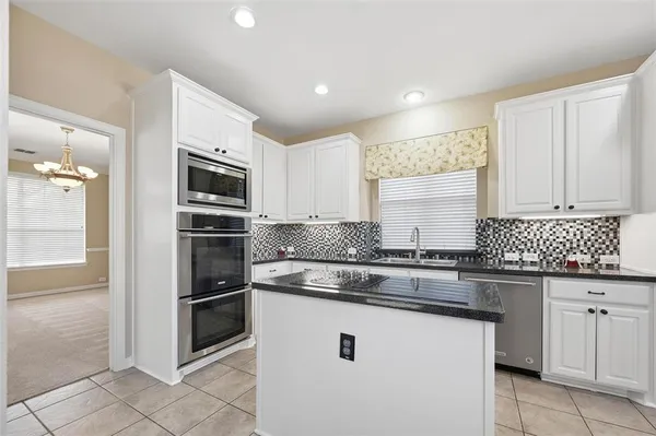 a kitchen with kitchen island granite countertop white cabinets and stainless steel appliances
