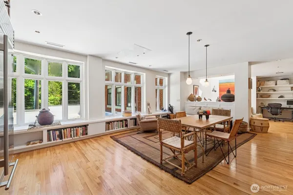 a living room with furniture large windows and wooden floor