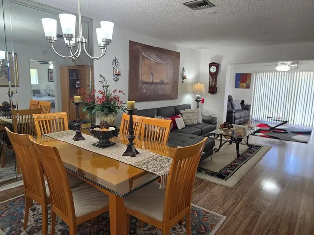 a view of a dining room with furniture a chandelier and wooden floor