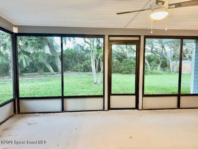 a view of an empty room with wooden floor and floor to ceiling windows