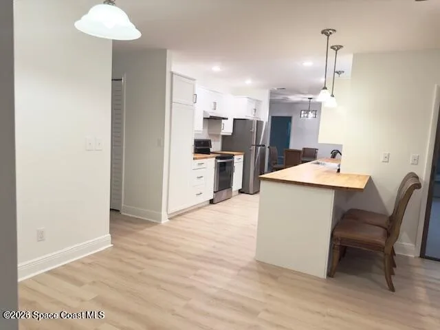 a room with kitchen island a dining table wooden floor and a view of kitchen