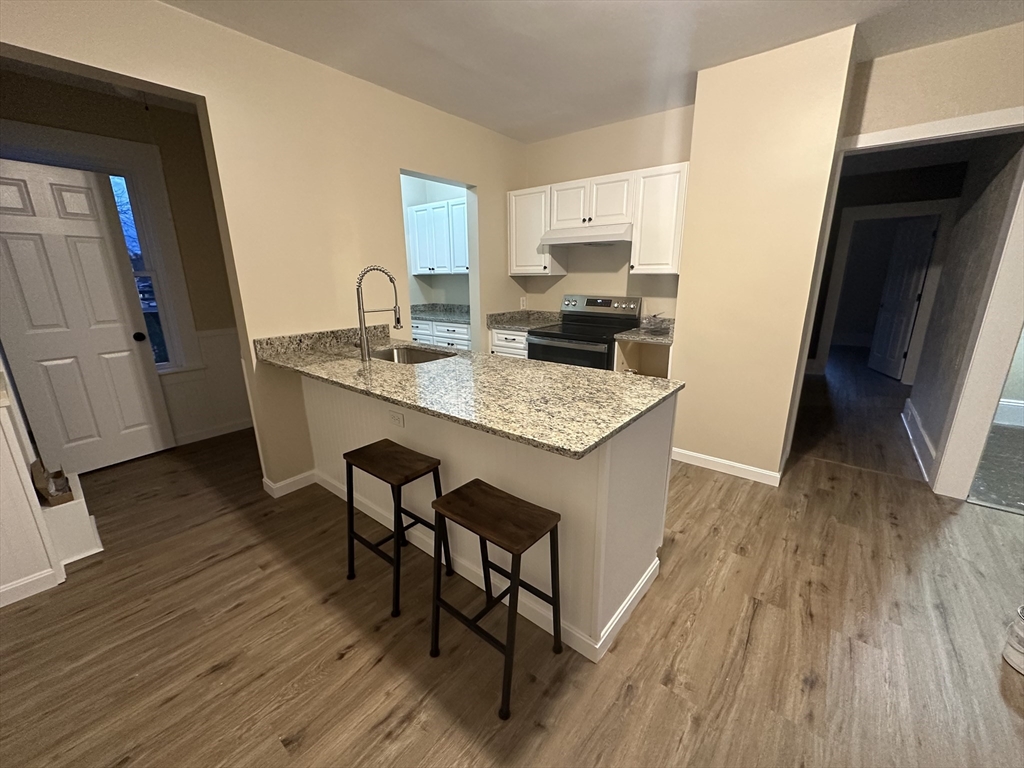 a kitchen with stainless steel appliances granite countertop wooden floors a stove top oven and a refrigerator