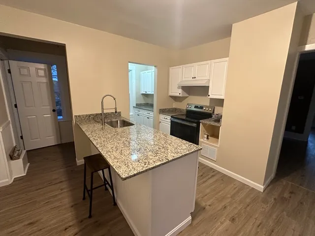a kitchen with granite countertop kitchen island wooden floors and stainless steel appliances