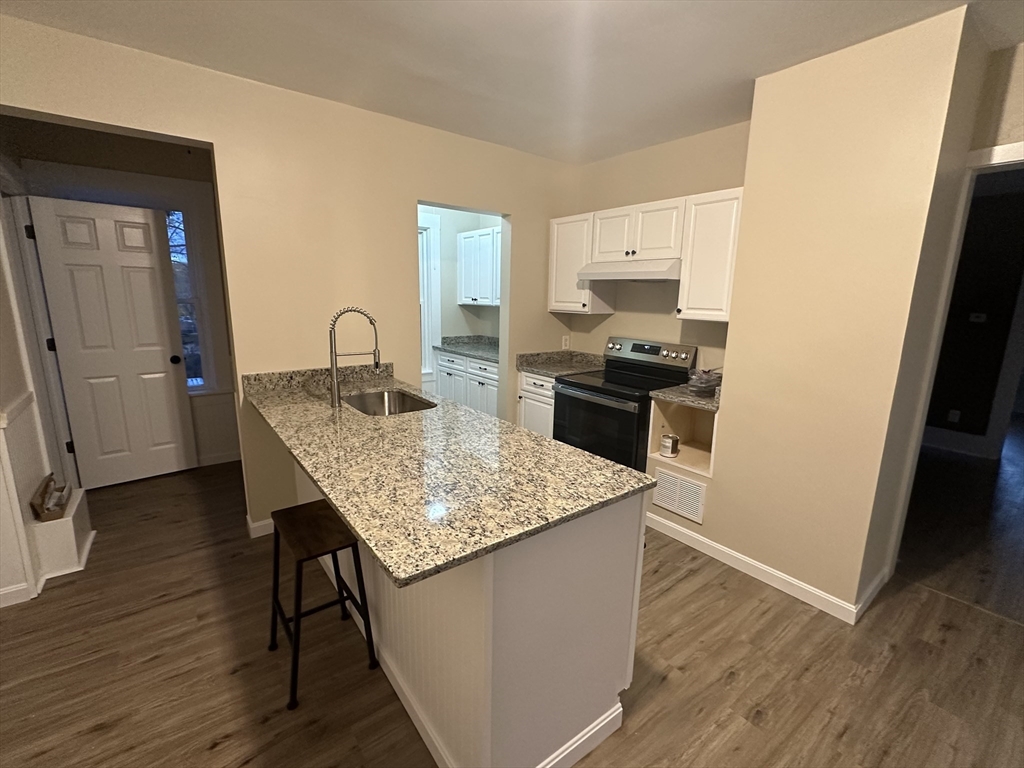 71 Flagg Street, Unit 2 Clinton, MA 01510 - Photo 3 of 13 a kitchen with granite countertop kitchen island wooden floors and stainless steel appliances