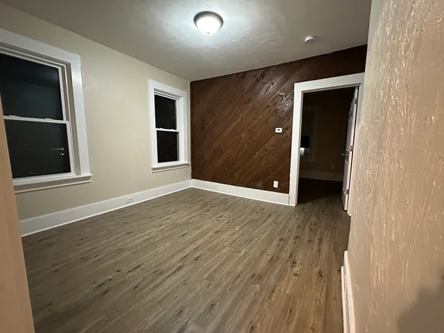a view of an empty room with wooden floor and closet