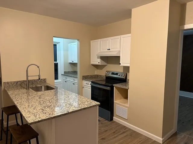 a kitchen with granite countertop a sink cabinets and stainless steel appliances