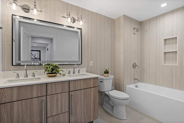 a bathroom with a toilet a sink a tub and mirror