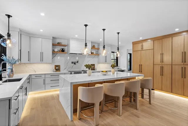 a kitchen with kitchen island granite countertop a table chairs sink and cabinets
