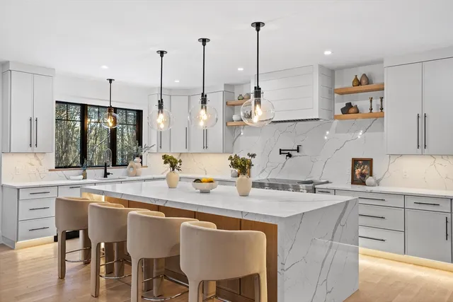a kitchen with stainless steel appliances granite countertop a sink a stove and chairs