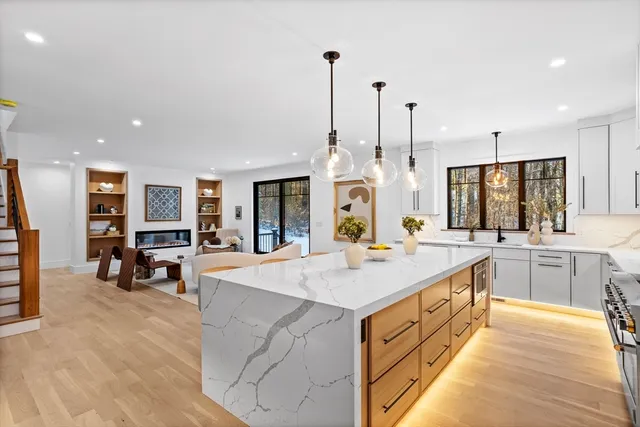 a large kitchen with kitchen island a stove a sink a oven a dining table and chairs with wooden floor