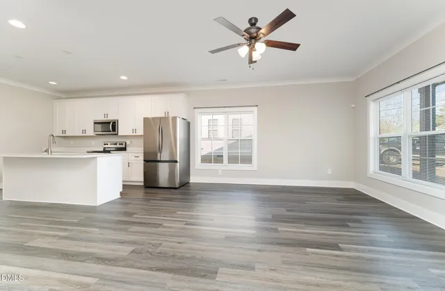 a kitchen with stainless steel appliances a stove a sink a refrigerator white cabinets and a refrigerator