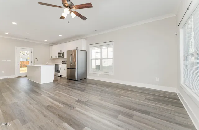 a kitchen with stainless steel appliances a stove a sink cabinets and a wooden floor