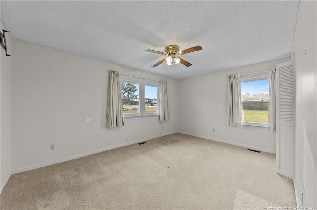 241 Hight Road Aberdeen, NC 28315 - Photo 20 of 48 an empty room with windows and chandelier fan