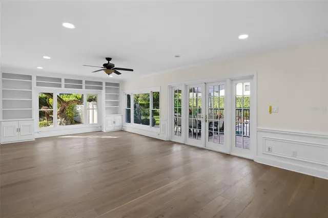 an empty room with floor to ceiling window and wooden floor