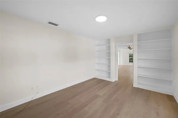 an empty room with windows and fan