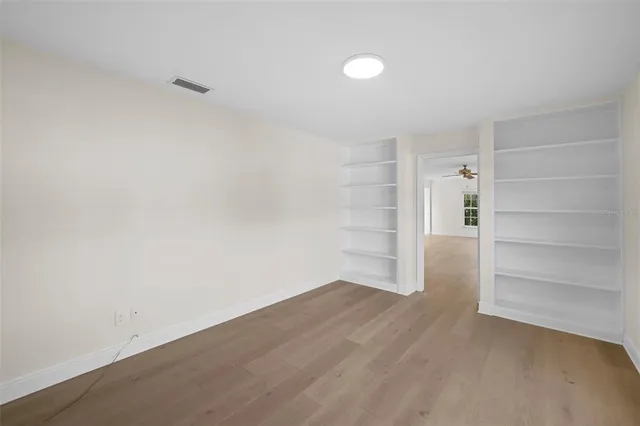 an empty room with windows and fan