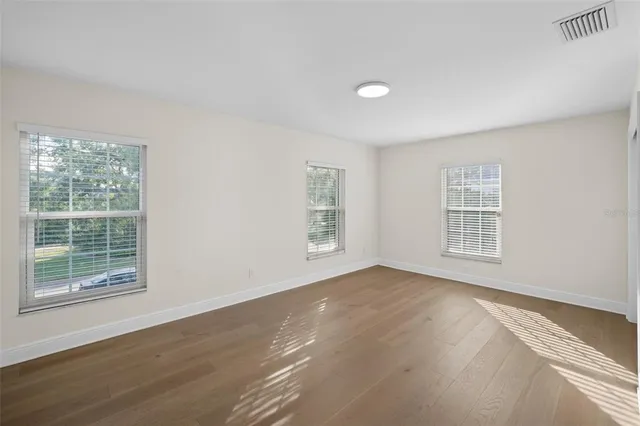 an empty room with windows and chandelier fan