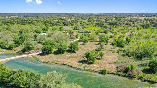 an aerial view of residential houses with outdoor space and trees all around