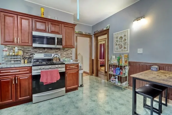 a kitchen with stainless steel appliances granite countertop a stove top oven a sink dishwasher a dining table and chairs with wooden floor